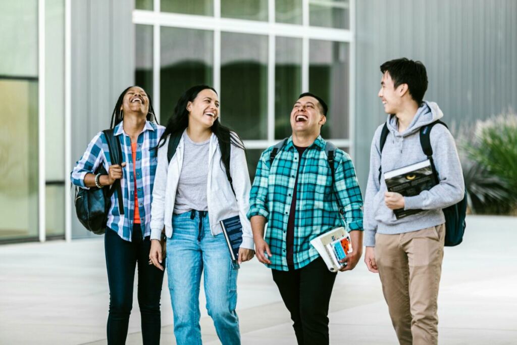 Four smiling college students walking outside